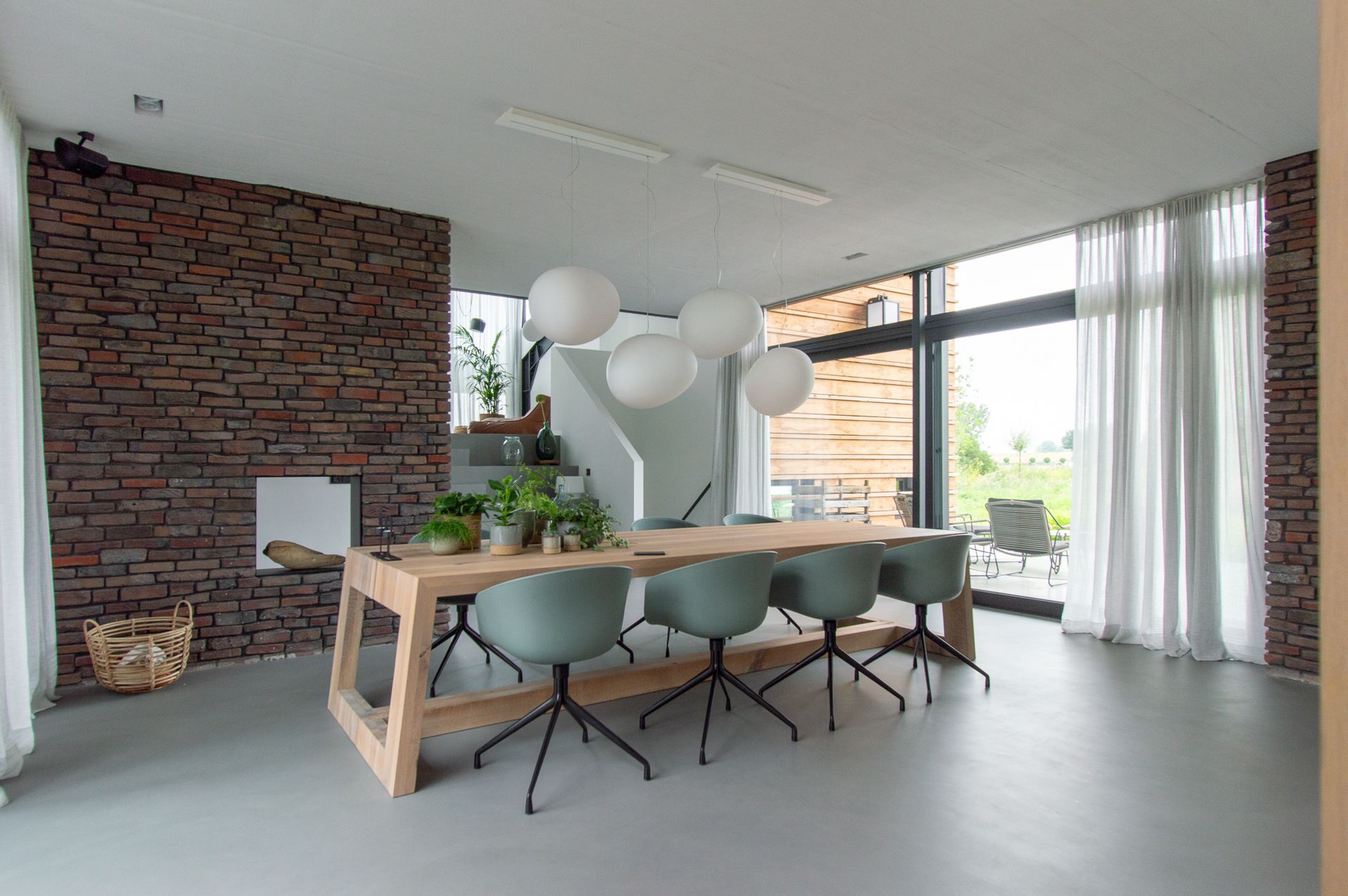 Een eetkamer met een lange houten tafel en stoelen.