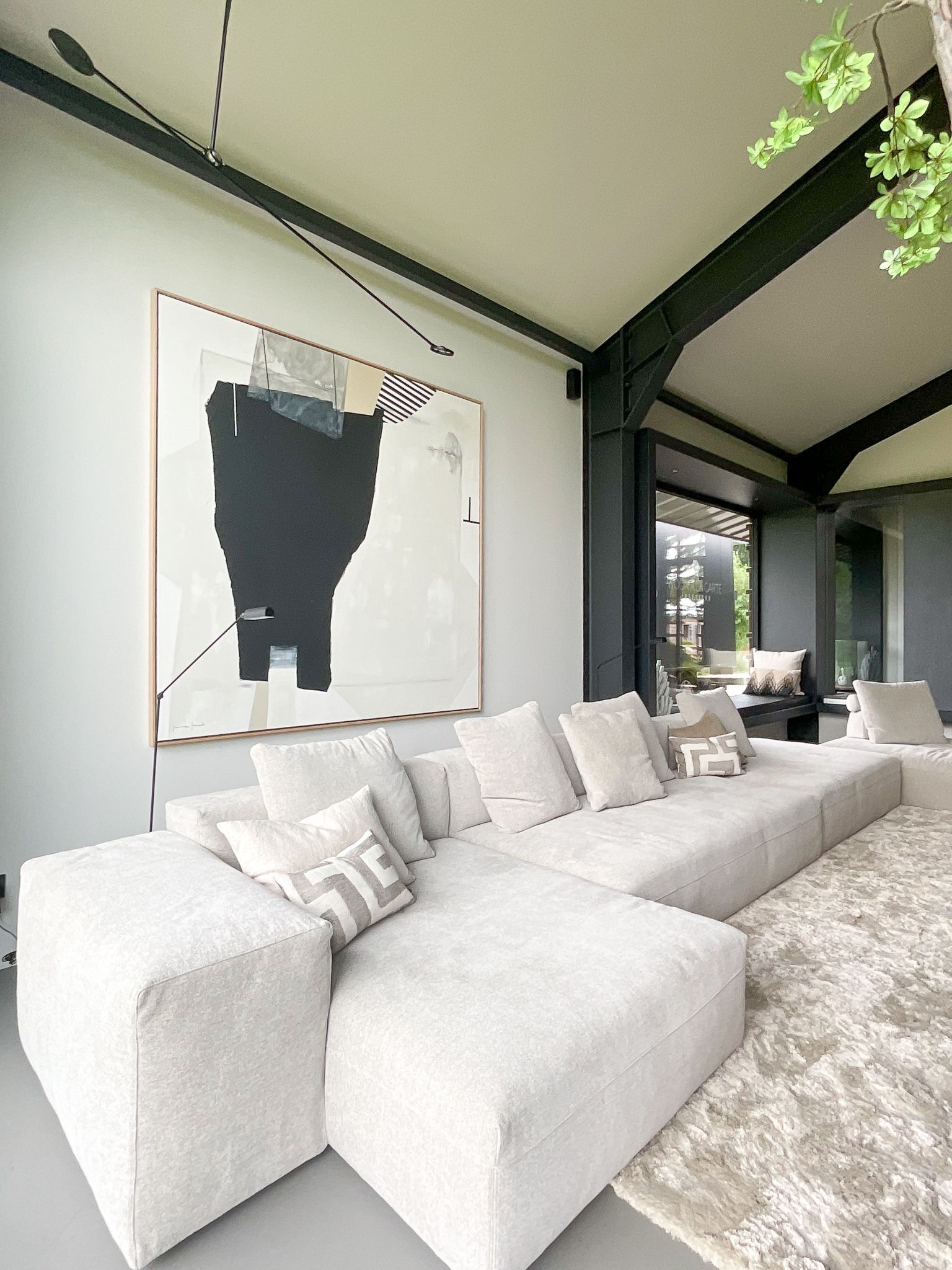 Er hangt een groot kunstwerk aan de muur boven de bank van Frigerio in de woonkamer.