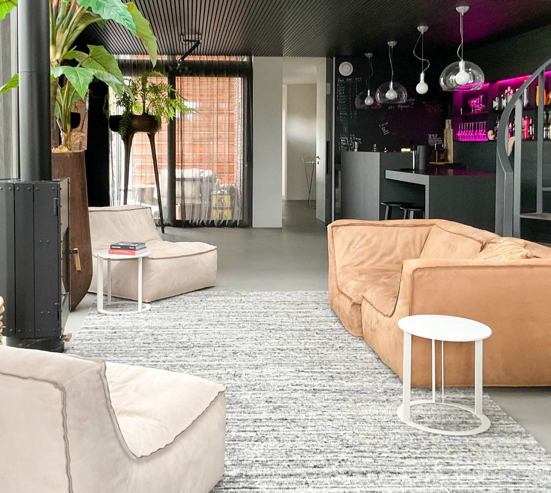 Een woonkamer met een bruine bank en witte stoelen