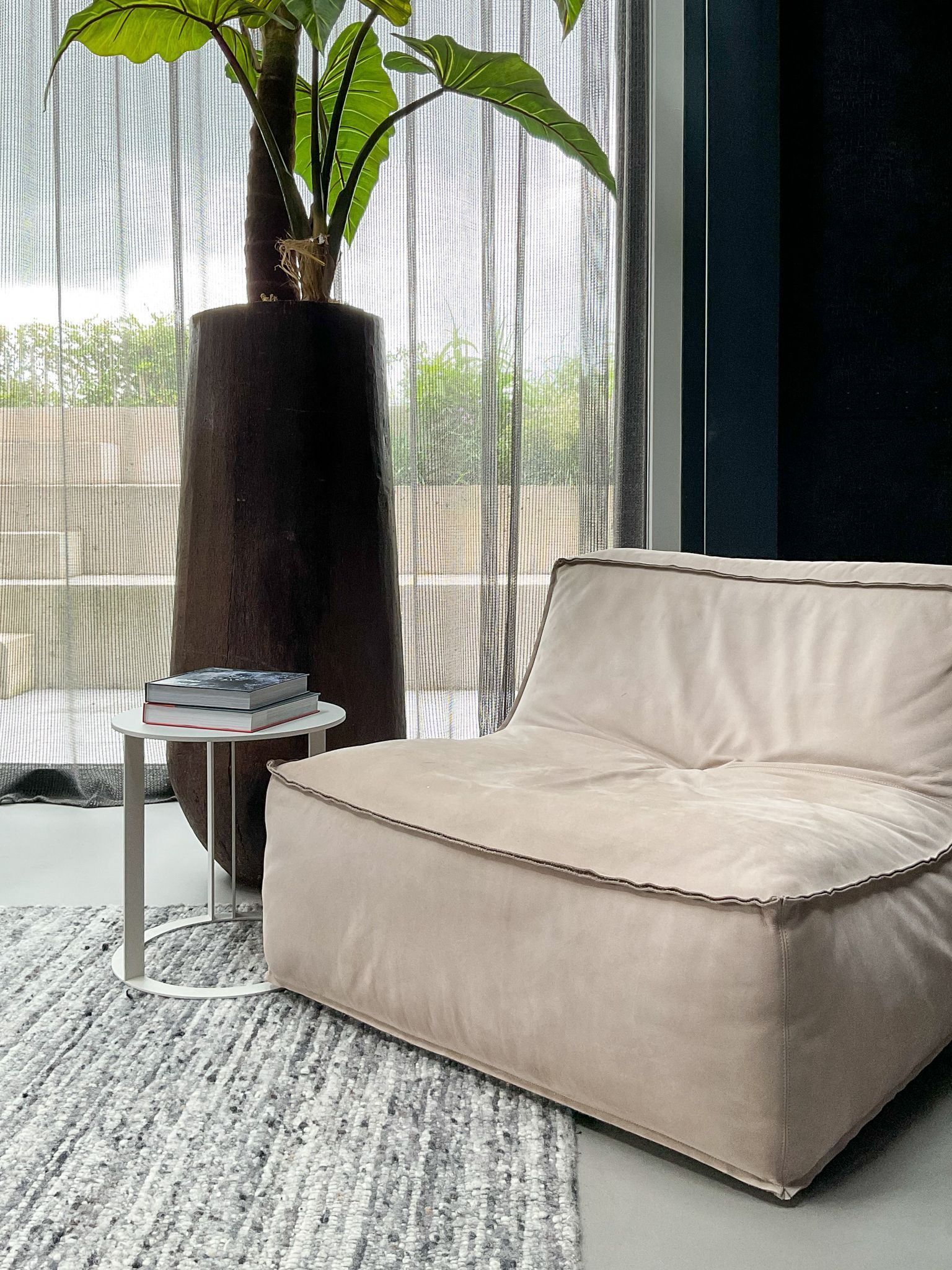 Er staat een fauteuil van Verzelloni in de woonkamer naast een grote potplant.