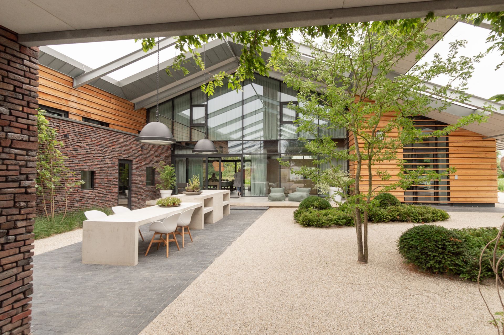 Een schuurwoning met veel ramen en bomen ervoor