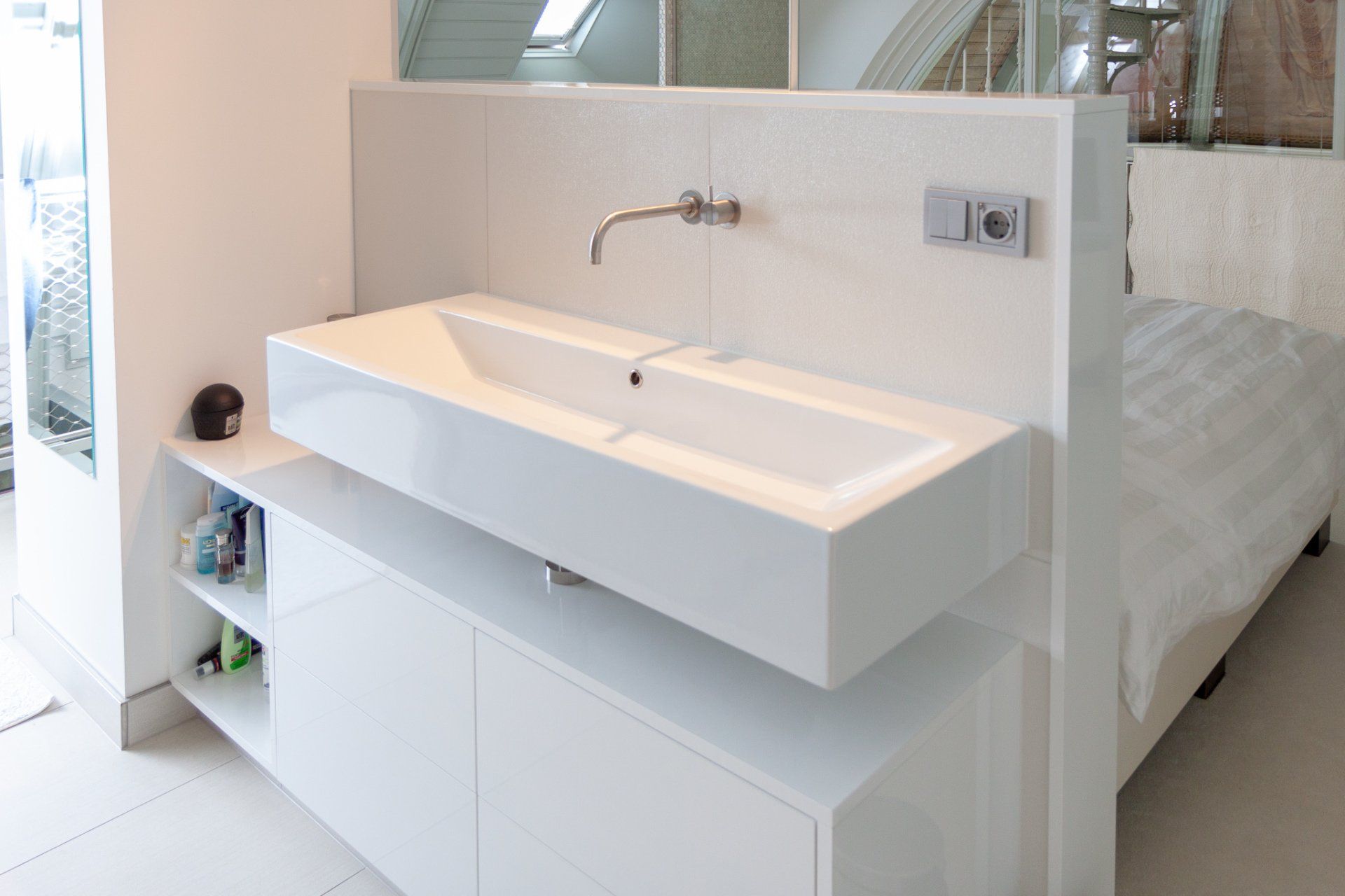 Een badkamer met een wastafel en een bed op de achtergrond