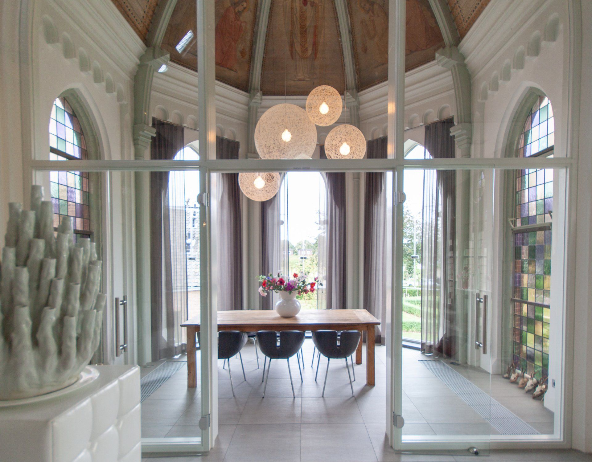 Een eetkamer met een tafel, stoelen en glas-in-loodramen