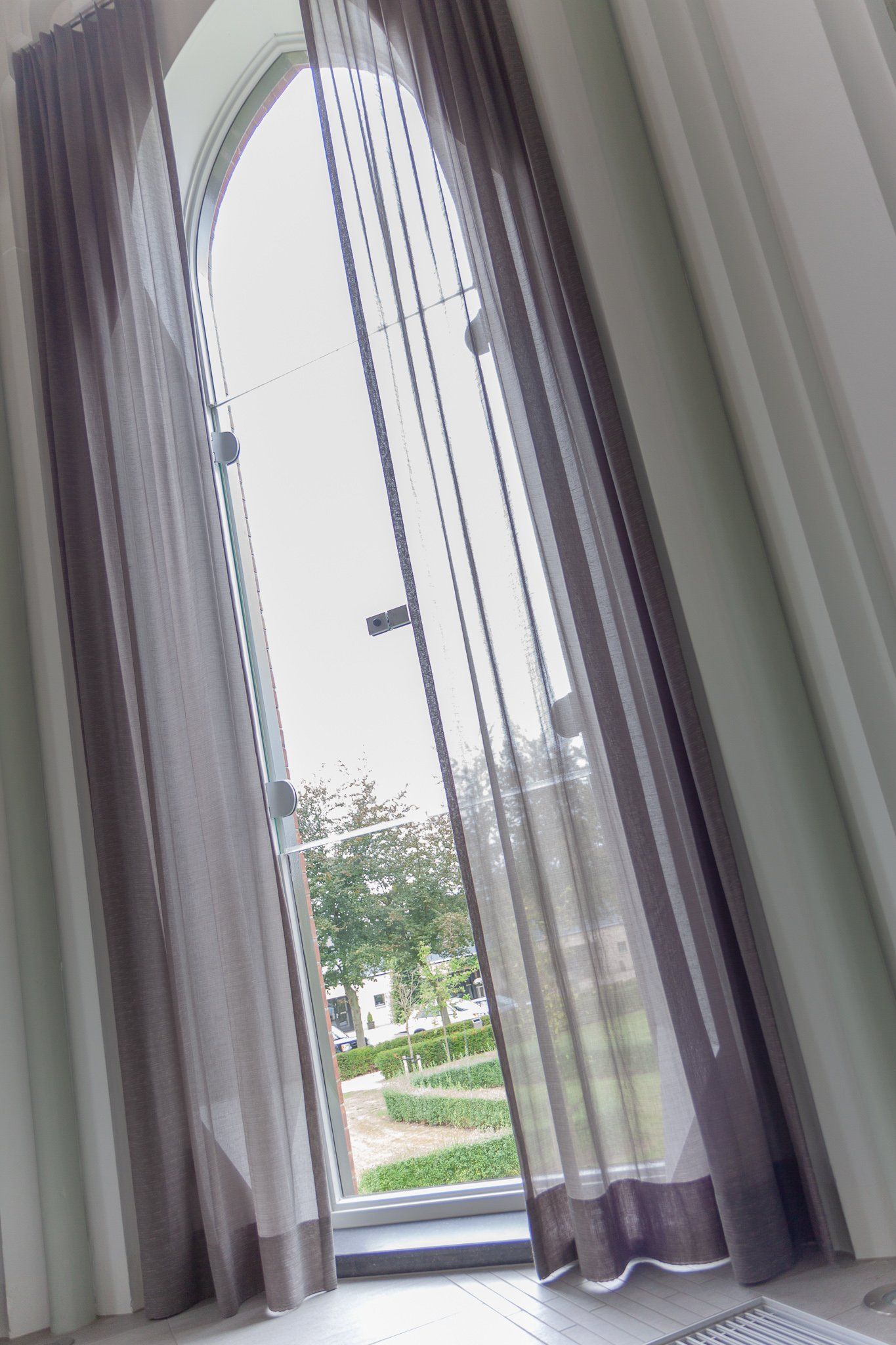 Een kamer met een open deur en een raam met gordijnen ervoor.