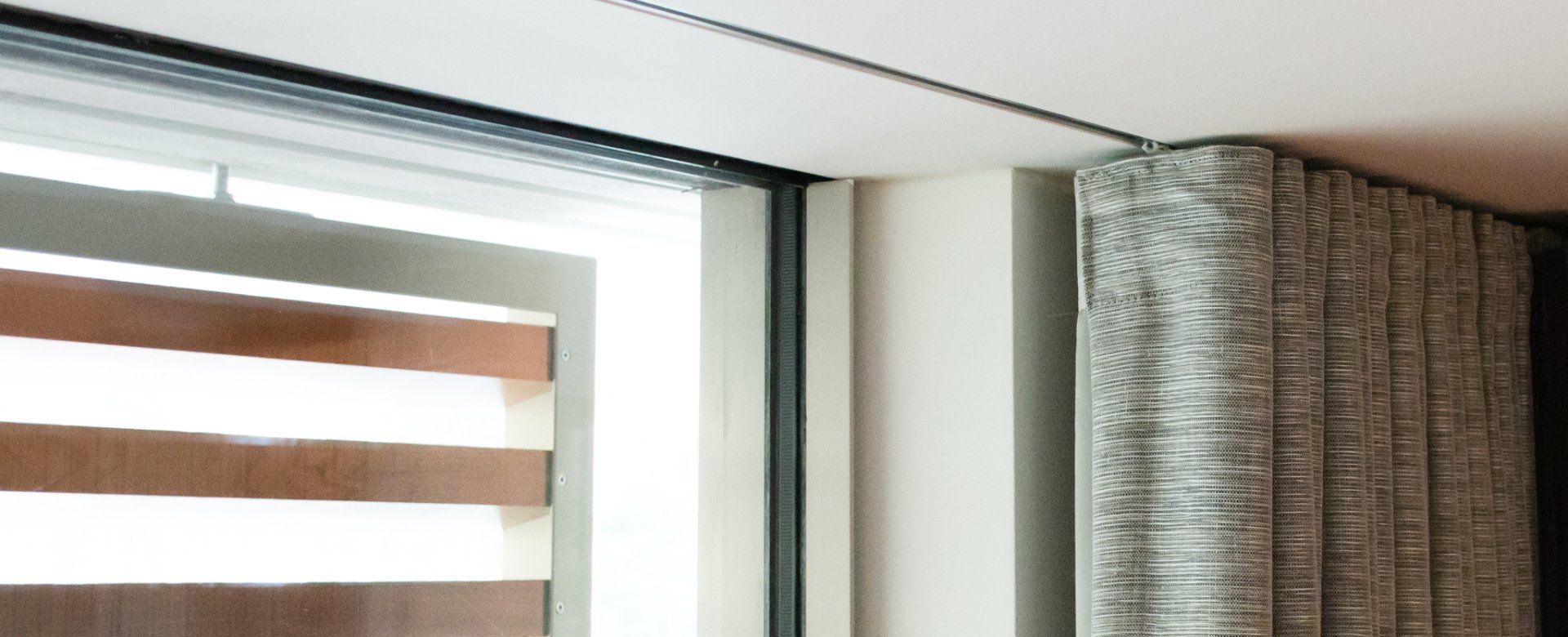 Een close-up van een raam met een gordijn dat aan het plafond hangt.