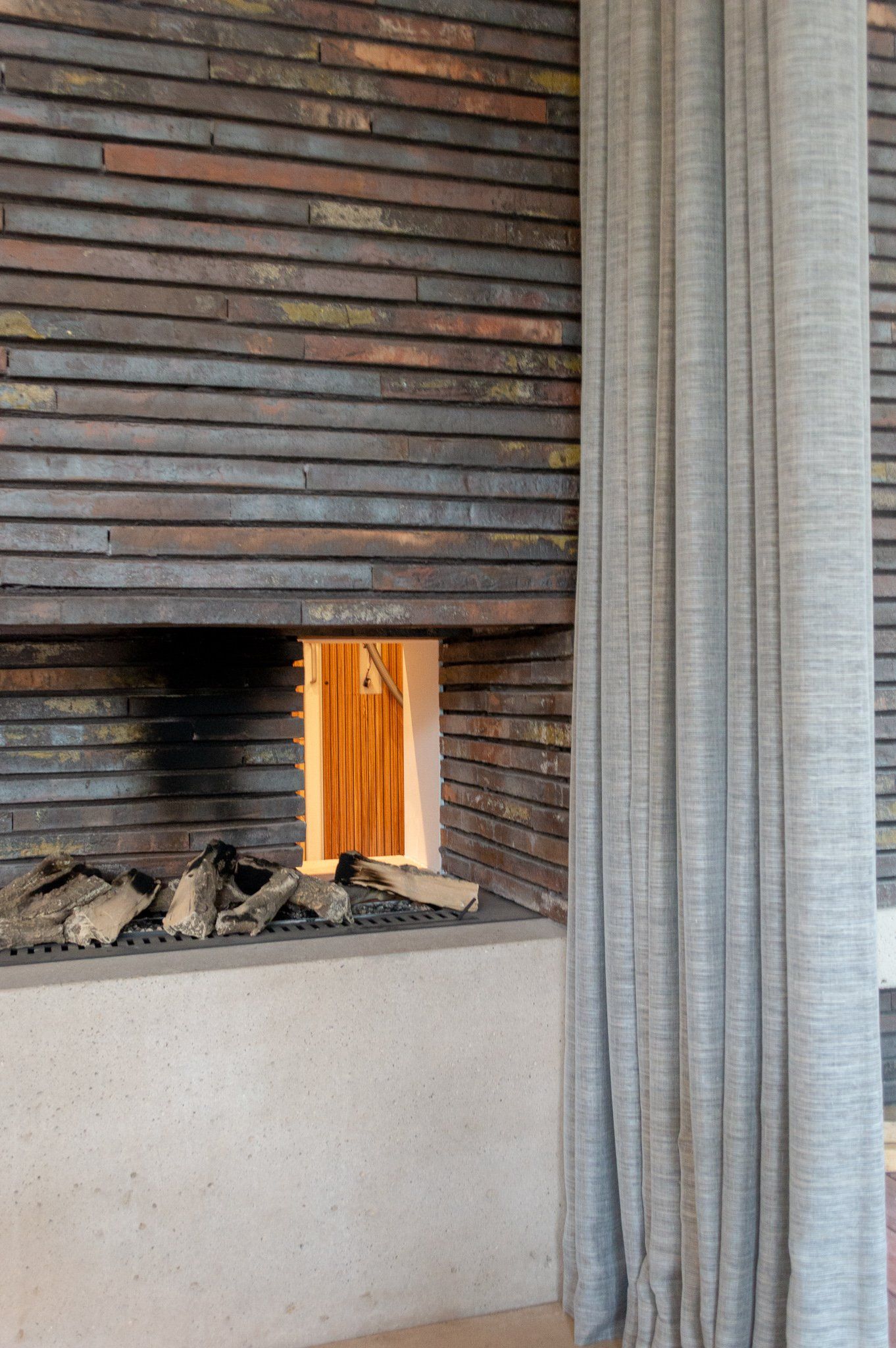 Een open haard is ingebouwd in een bakstenen muur in een woonkamer.