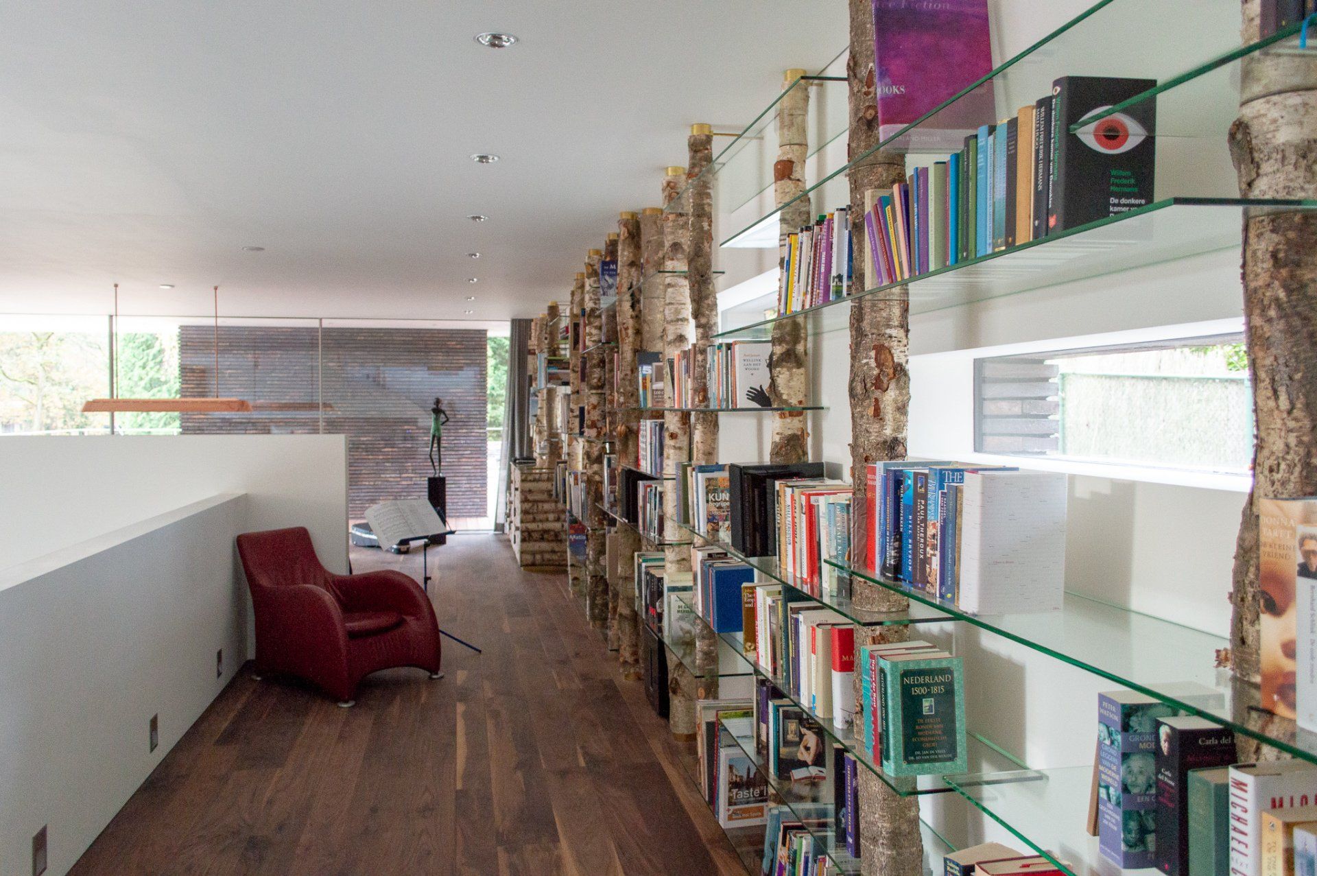 Een lange gang vol boeken en een rode stoel