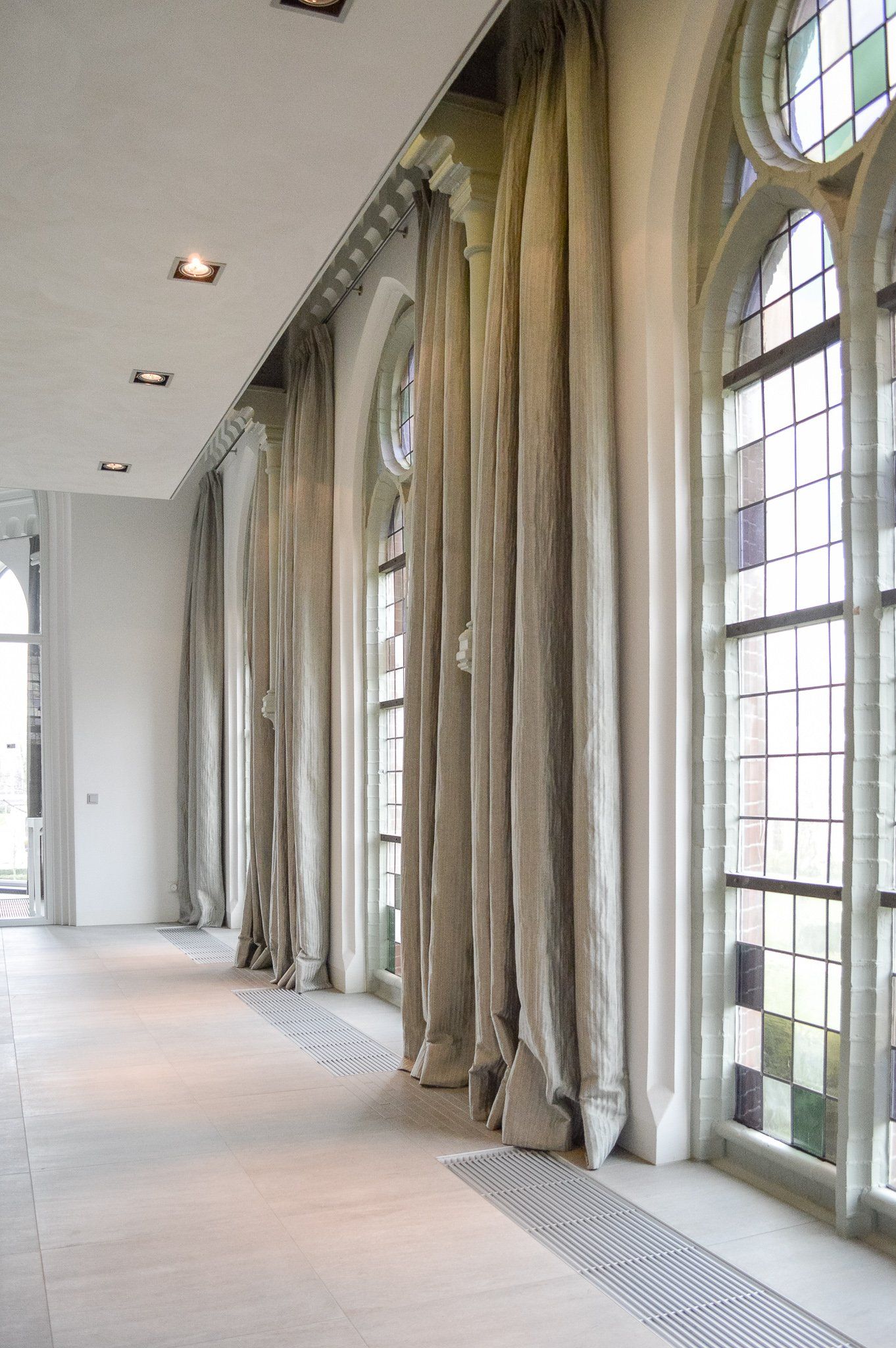 Een lange gang met veel ramen en gordijnen