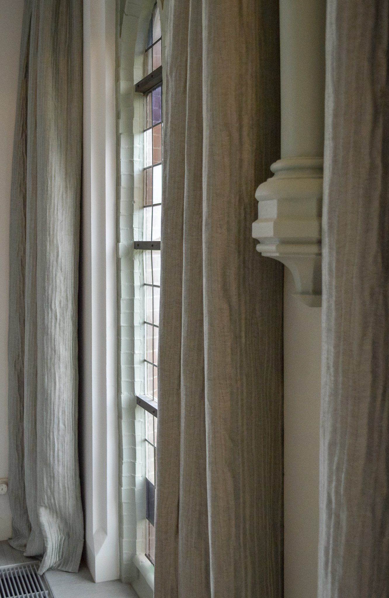 Een close-up van een raam met gordijnen en een glas-in-loodraam.