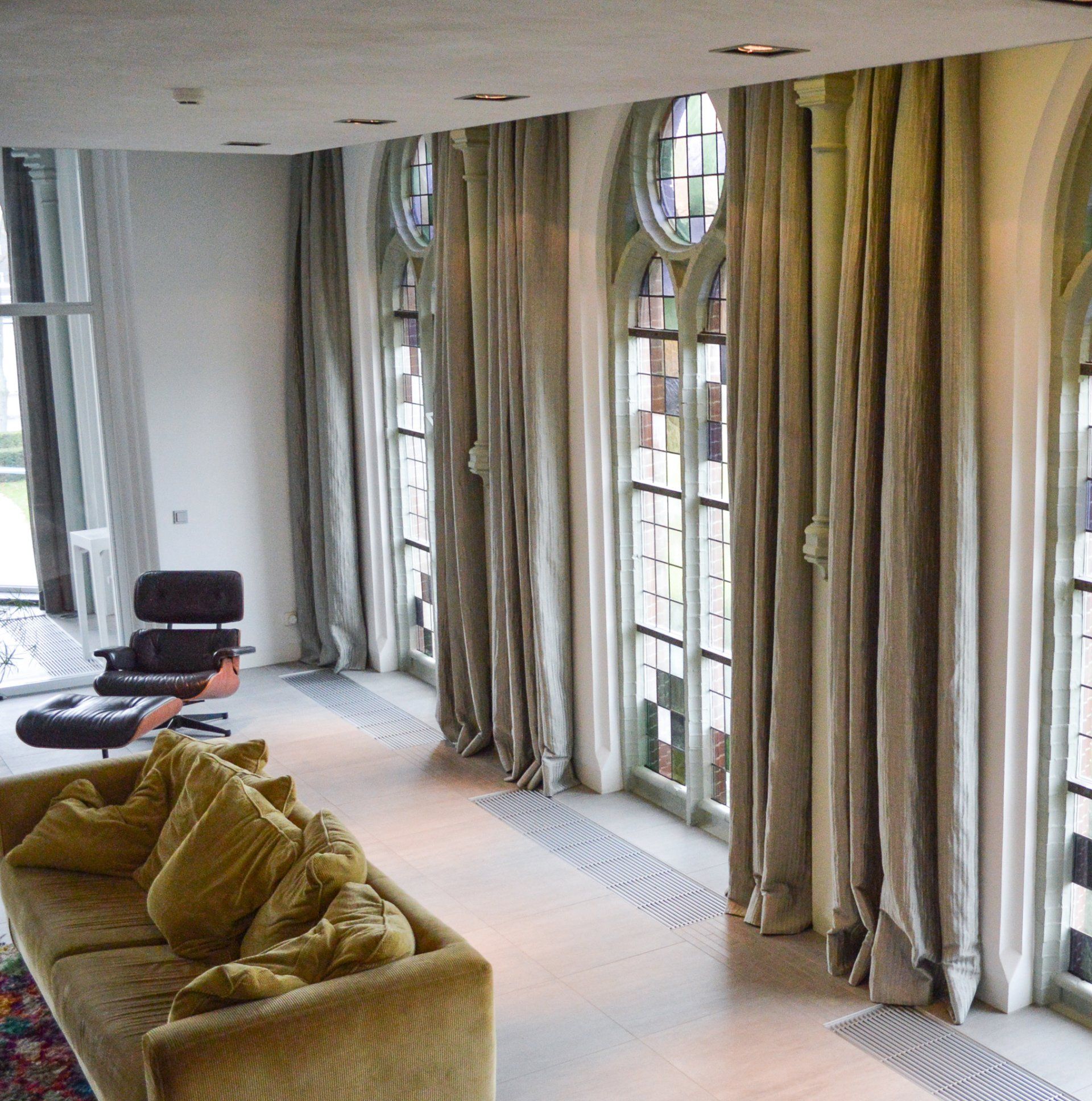 Een woonkamer met een bank en stoel en veel ramen