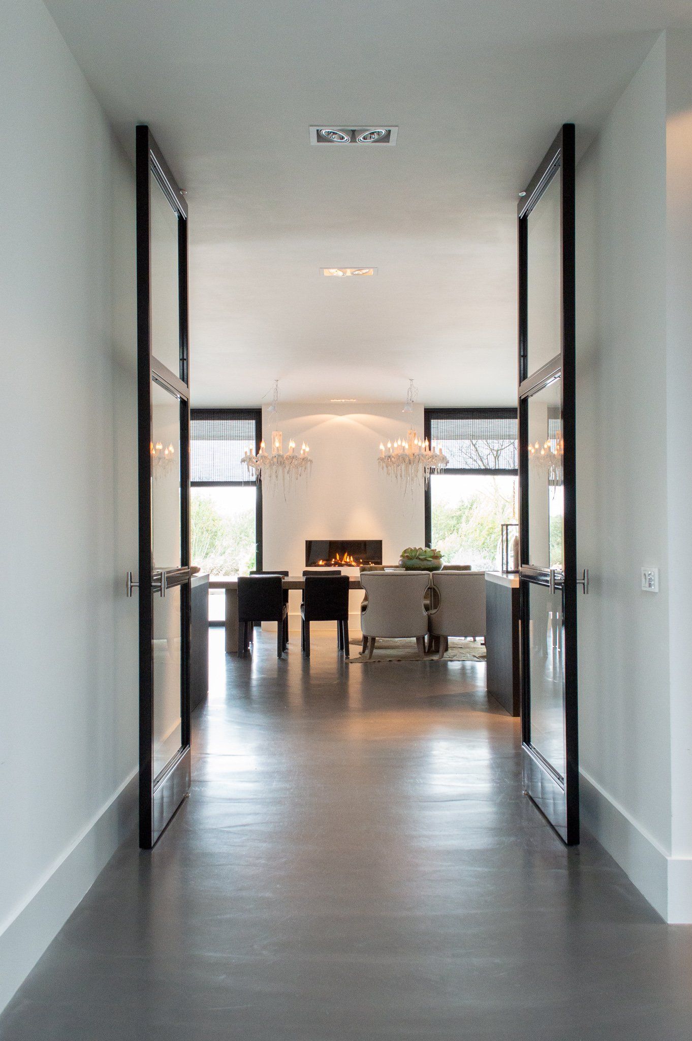 Een gang die leidt naar een eetkamer met een tafel en stoelen