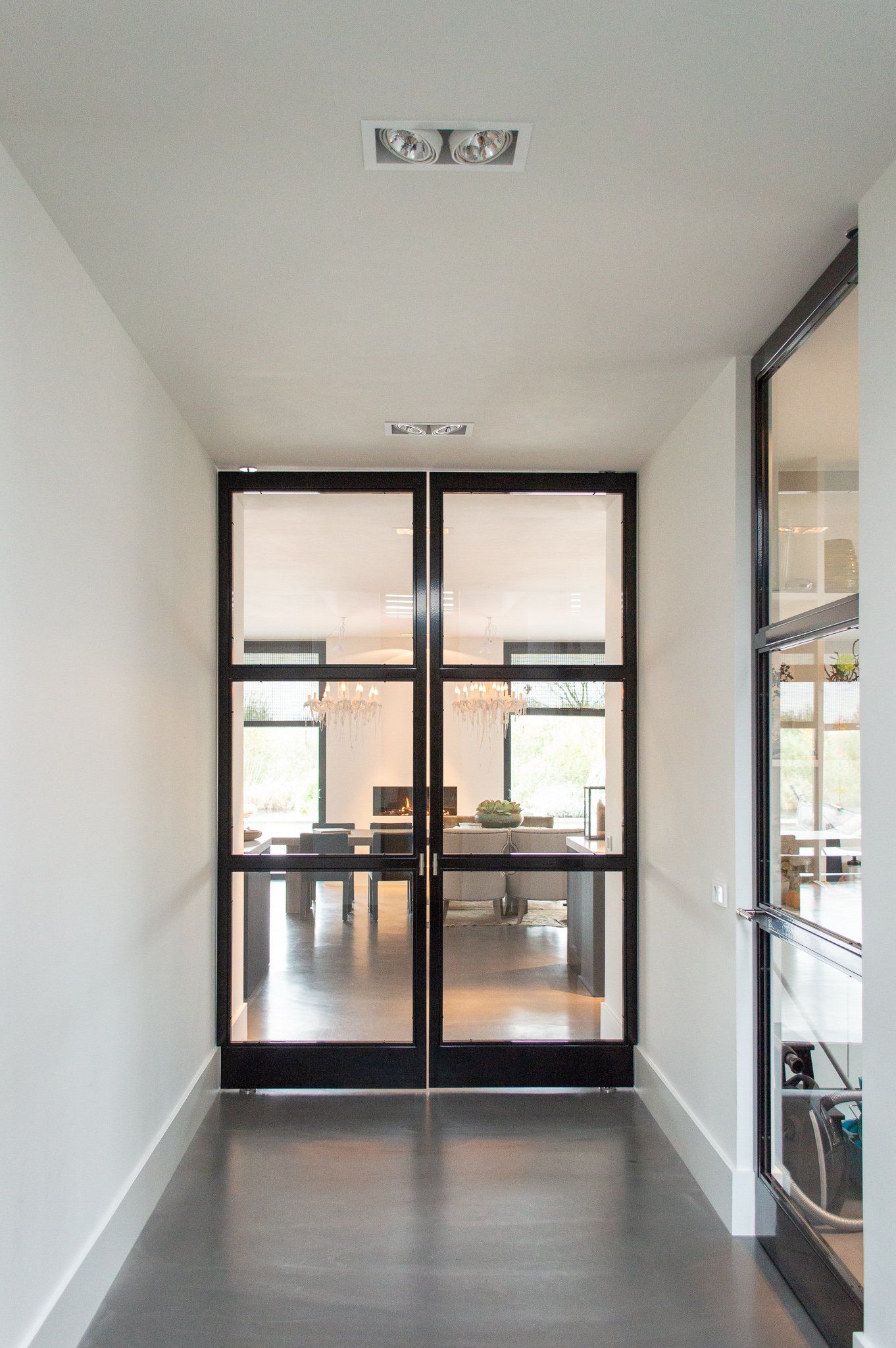 Een gang met glazen deuren die naar een eetkamer leiden