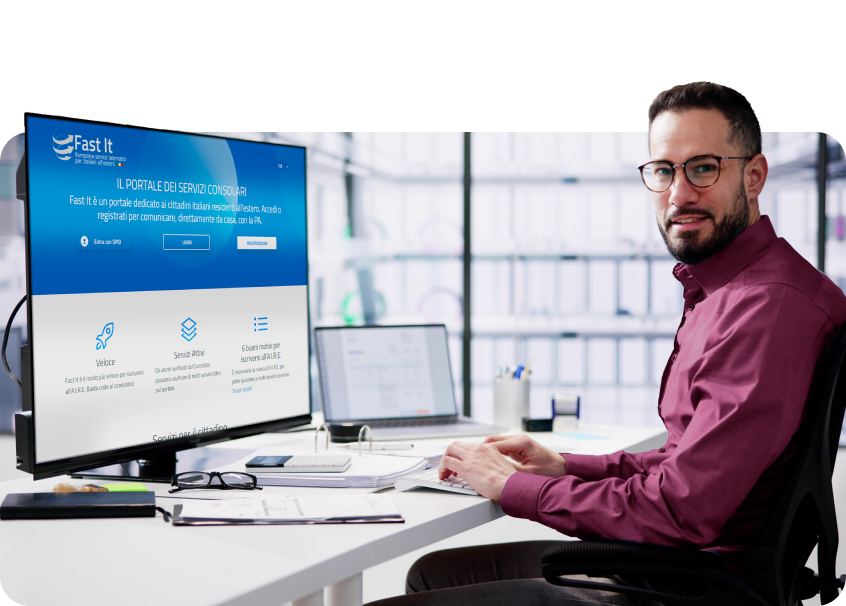 Um homem está sentado em uma mesa em frente a um computador.