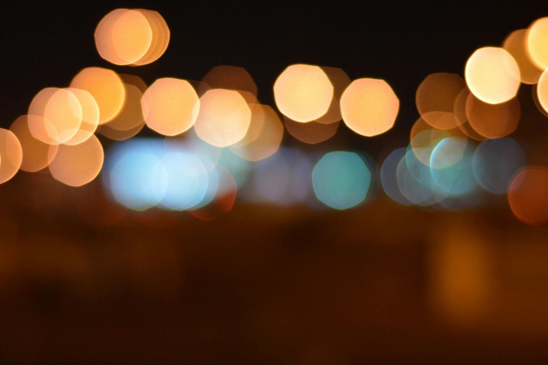 Bokeh lights in various shades of yellow, orange, and blue against a dark background, creating a blurred, abstract effect.