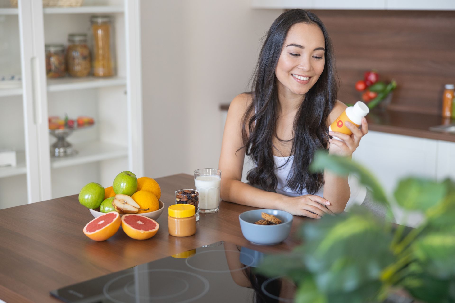 A woman is taking a supplement with her breakfast.
