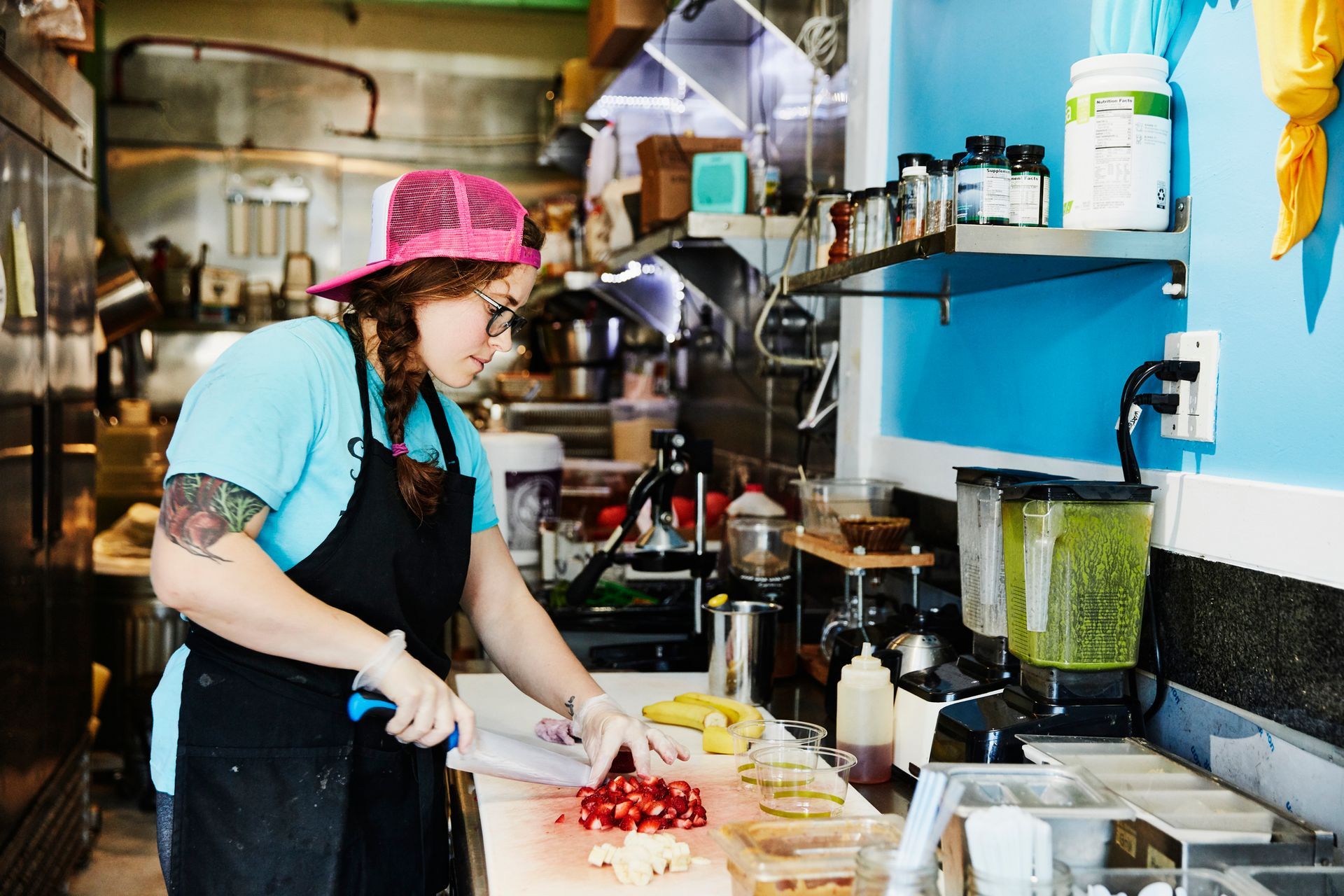 A juice bar owner is cutting fresh fruits.