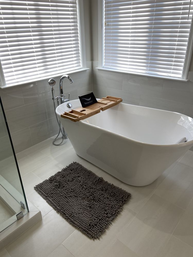 A bathroom with a bathtub and a window with blinds.