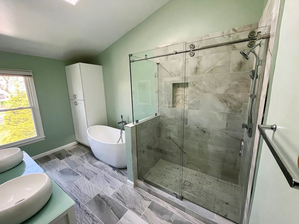 A bathroom with a tub , sinks and a walk in shower.