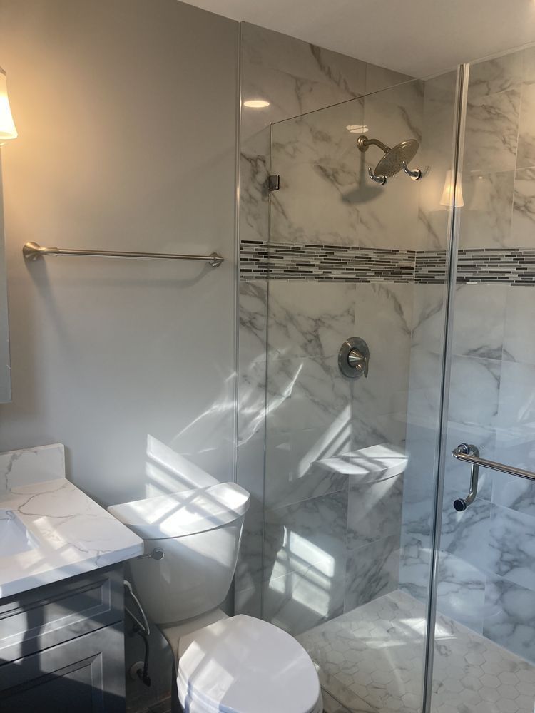 A bathroom with a toilet , sink and walk in shower.