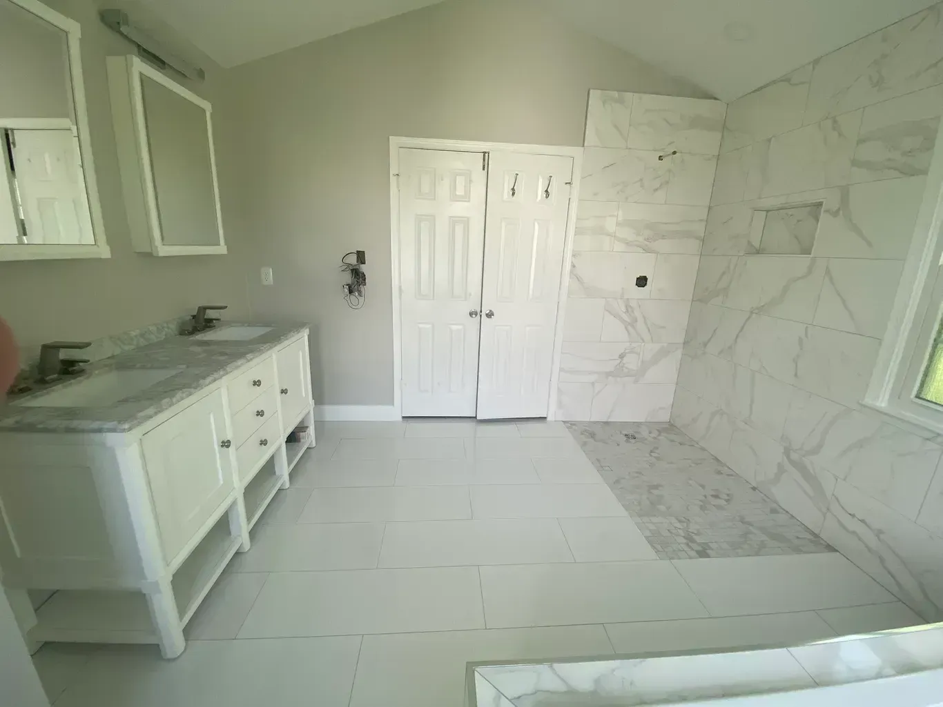 A bathroom with two sinks and a walk in shower.