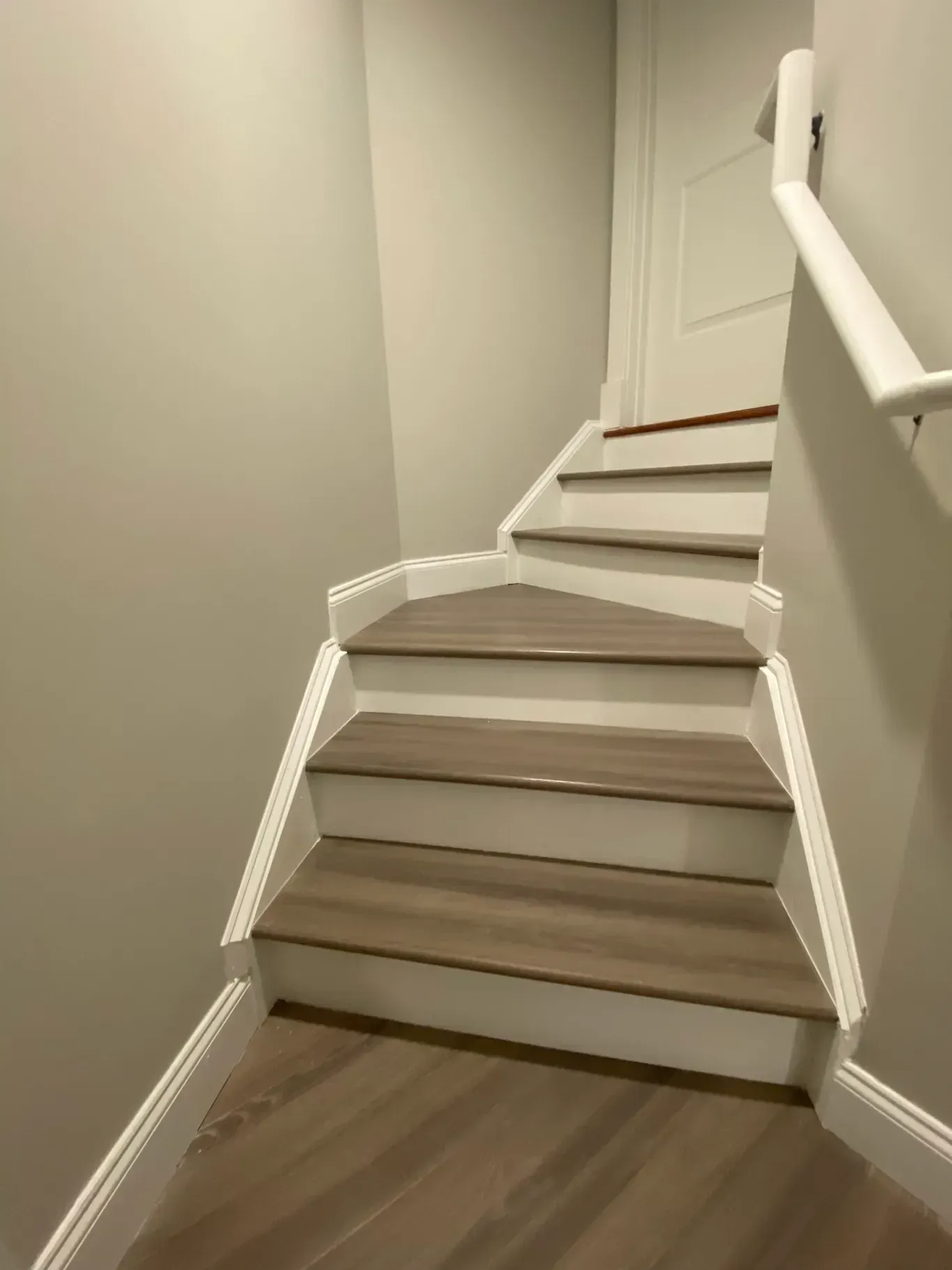 A set of stairs with wooden steps and a white railing in a room.