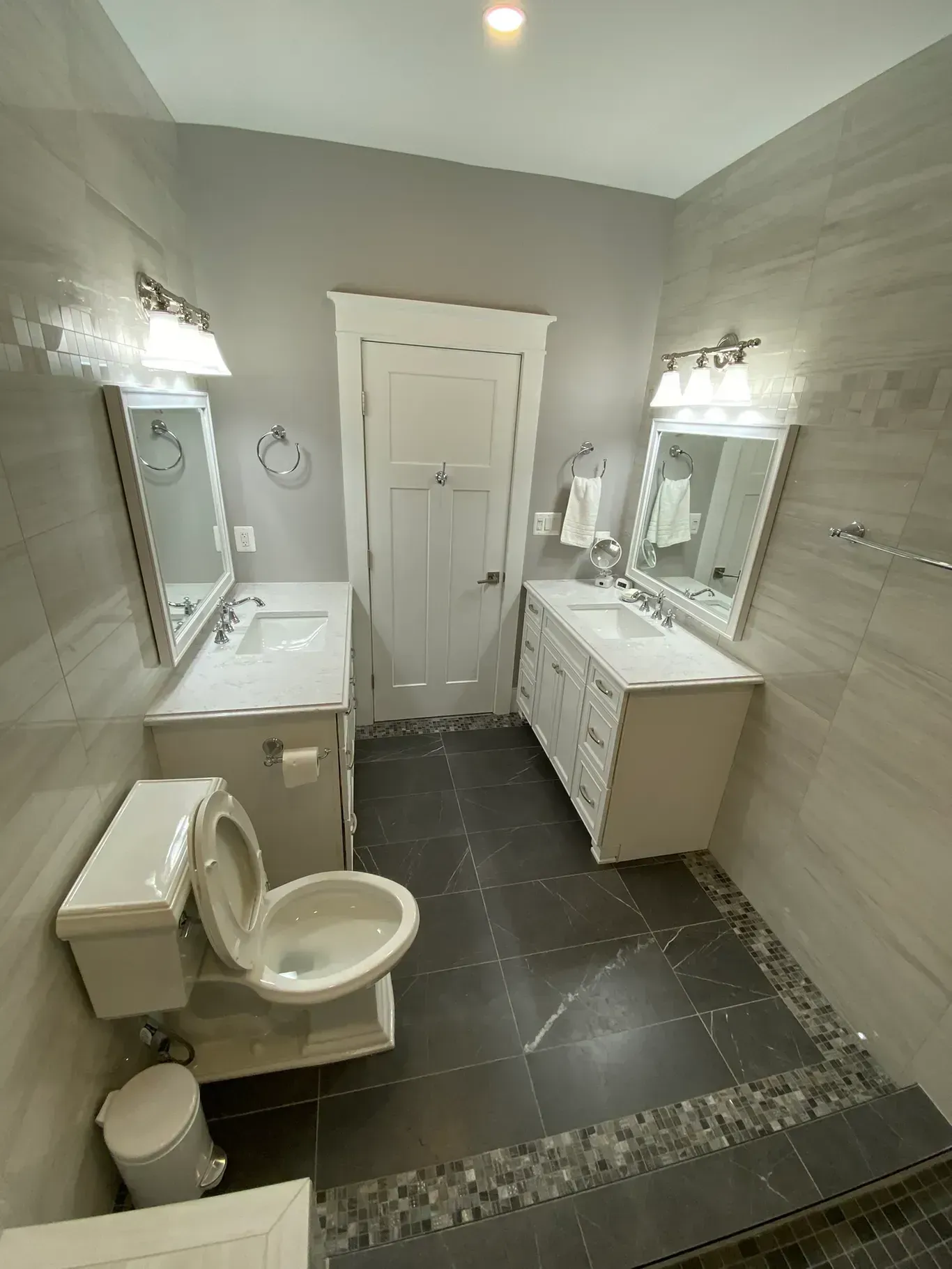 A bathroom with a toilet , sink and mirrors.