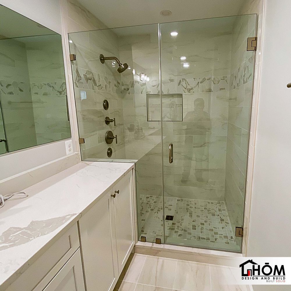 A bathroom with a glass shower door and a mirror
