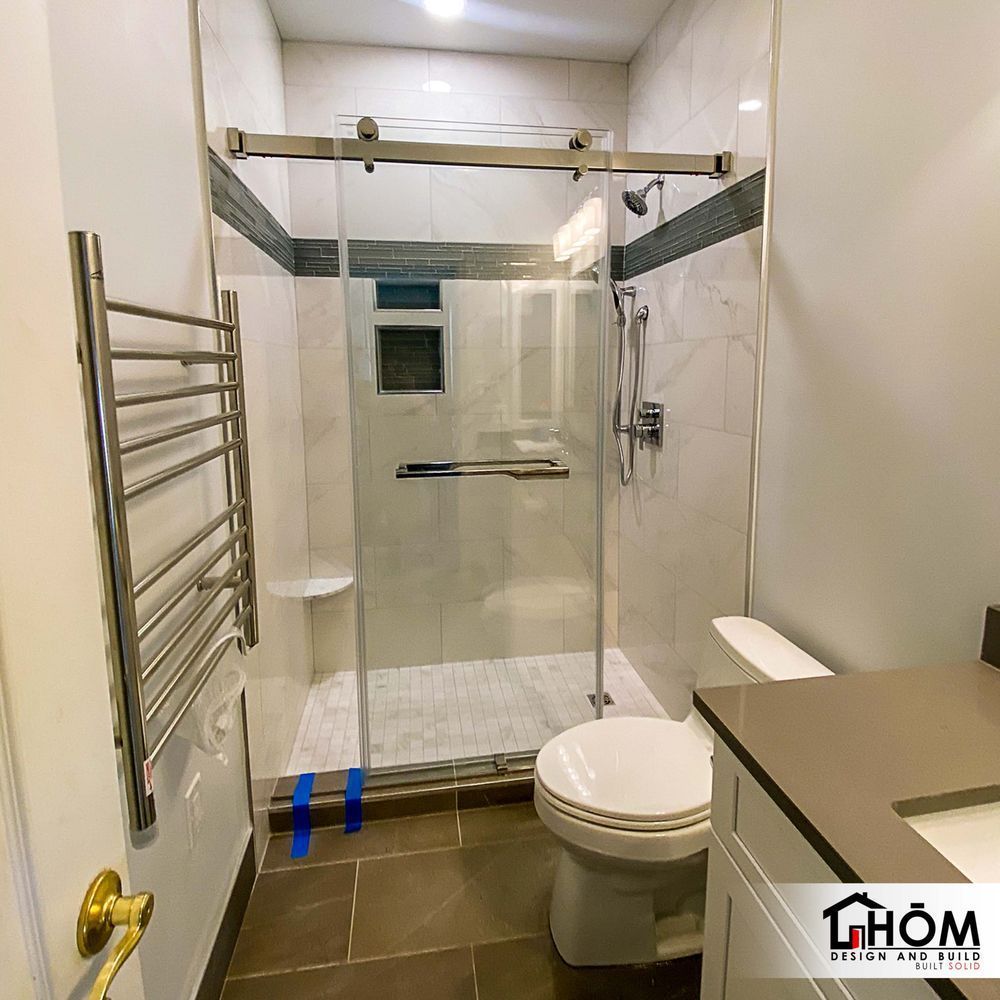 A bathroom with a toilet , shower , and towel rack.