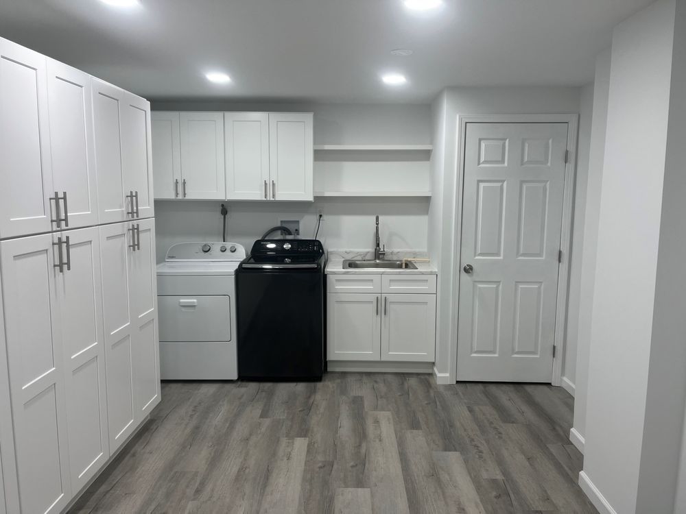 A laundry room with white cabinets and a black washer and dryer