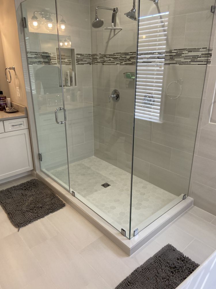 A bathroom with a walk in shower with a glass door.