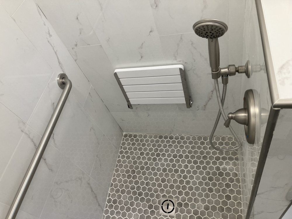 A shower with a seat and a shower head.