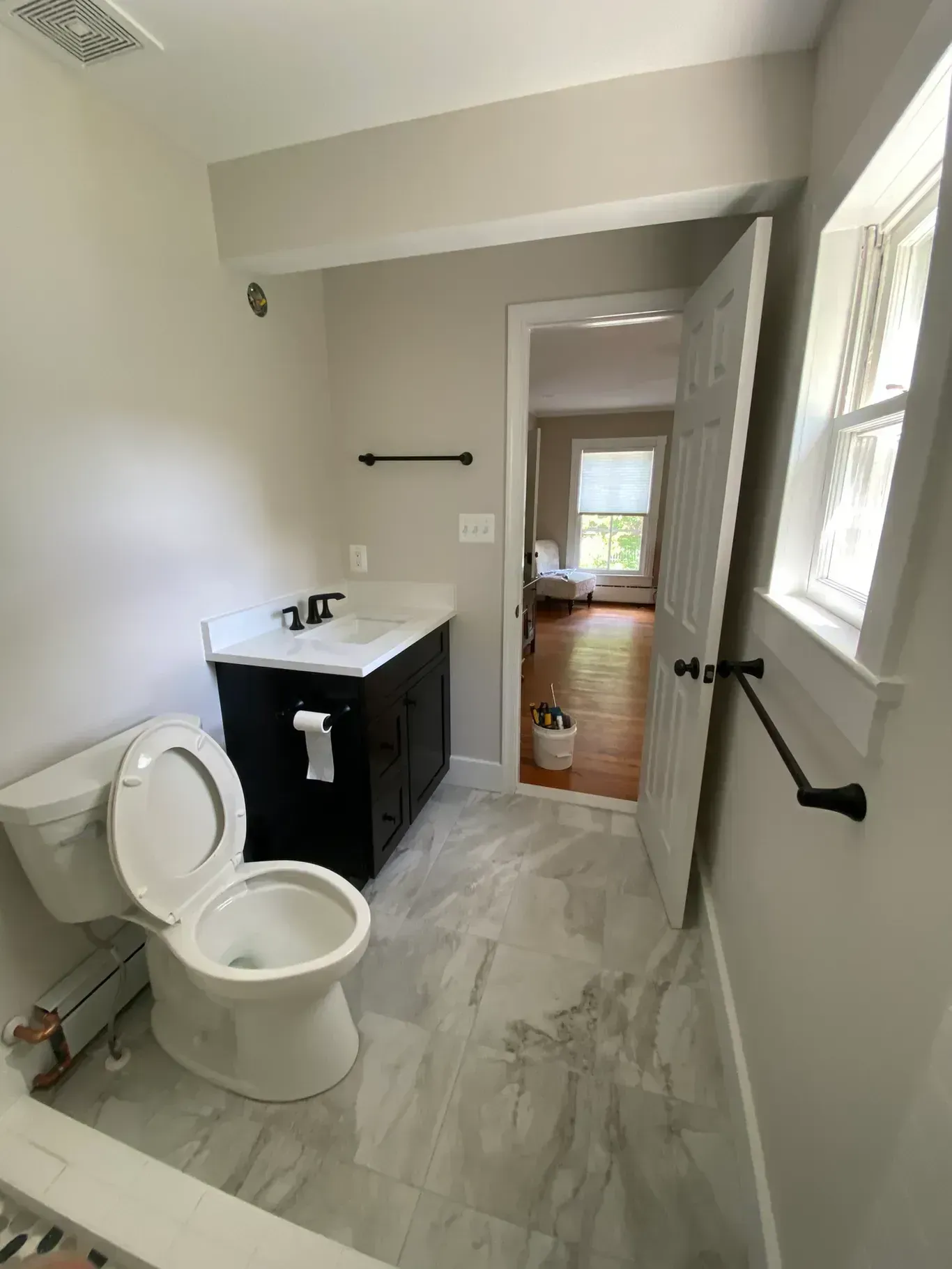 A bathroom with a toilet , sink , and window.