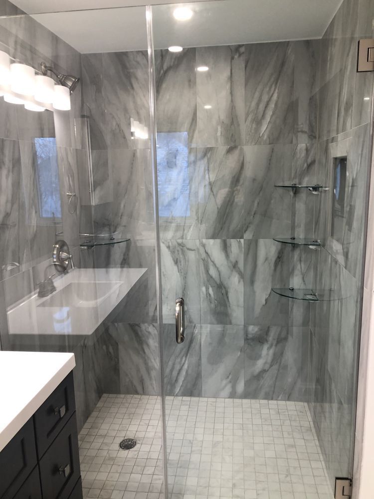A bathroom with a walk in shower and a sink