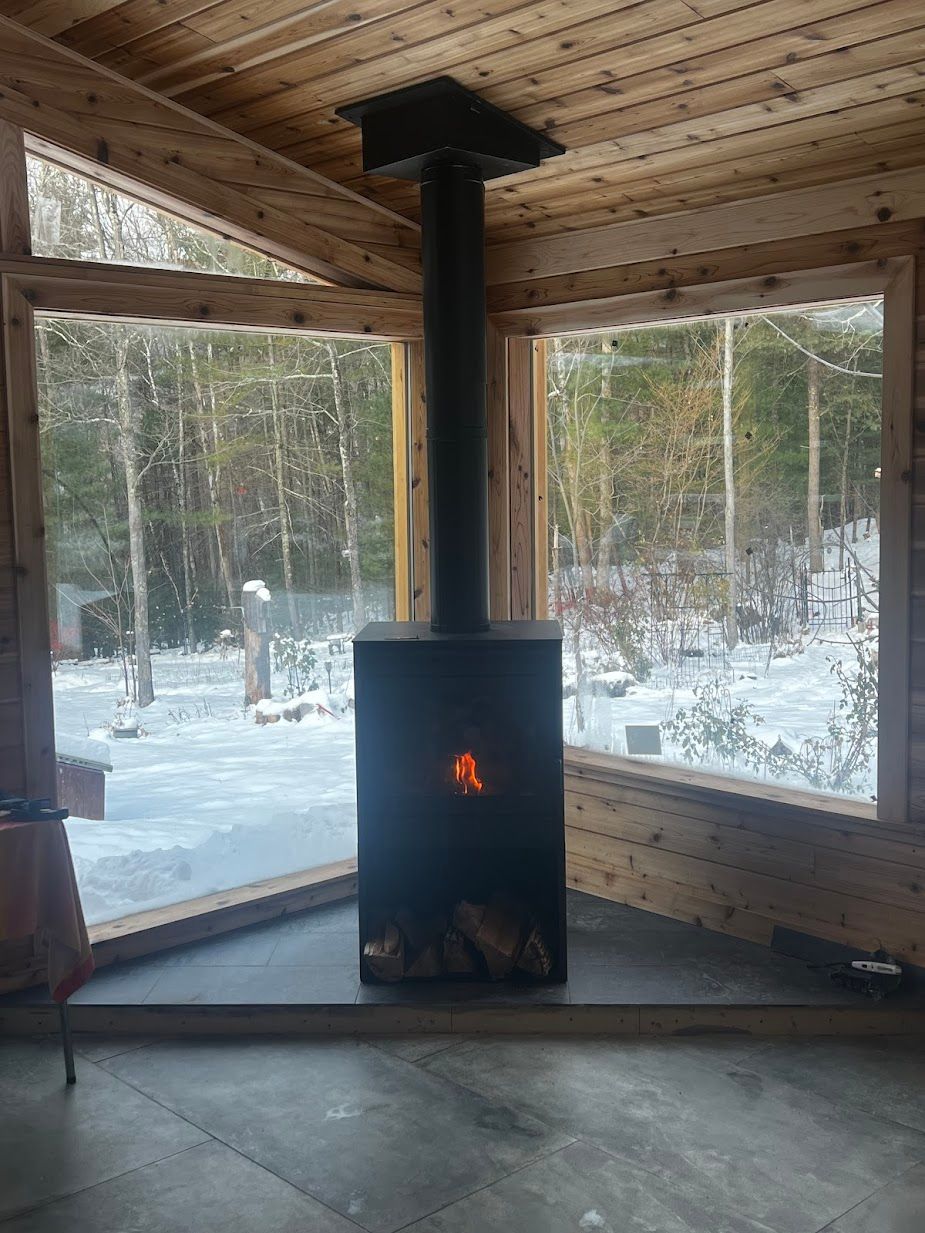 A wood stove is sitting in a room next to a window.
