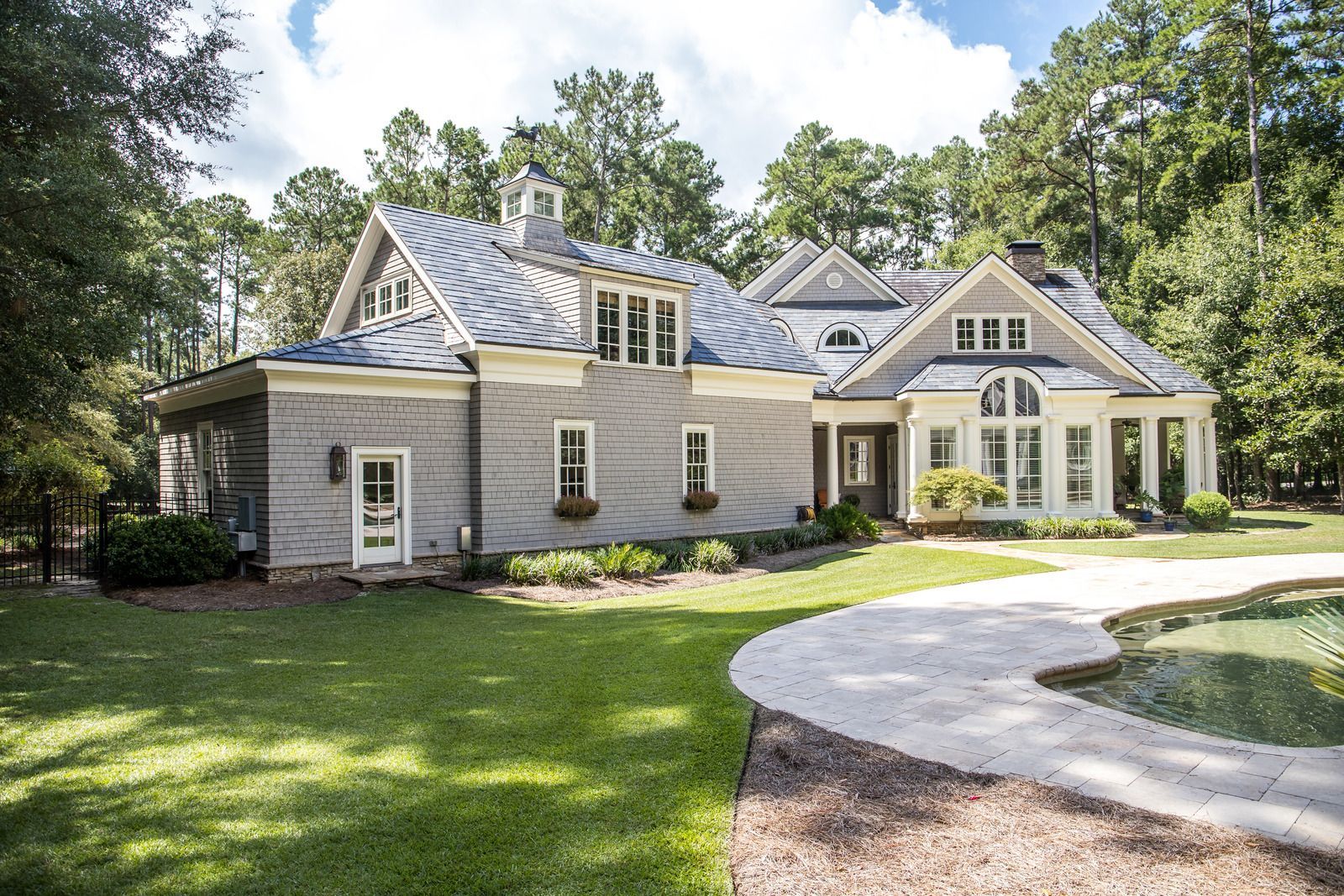 A large white house with a blue roof is surrounded by trees and grass.