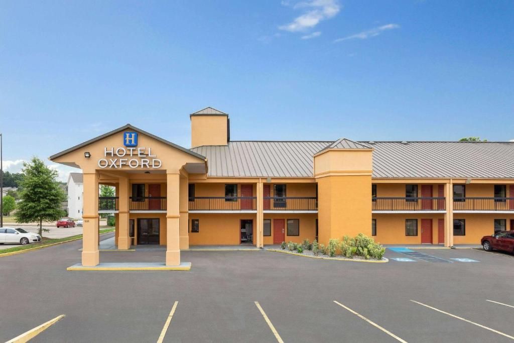Exterior of a Days Inn hotel with orange stucco walls, brown roof, and parking lot under a blue sky.