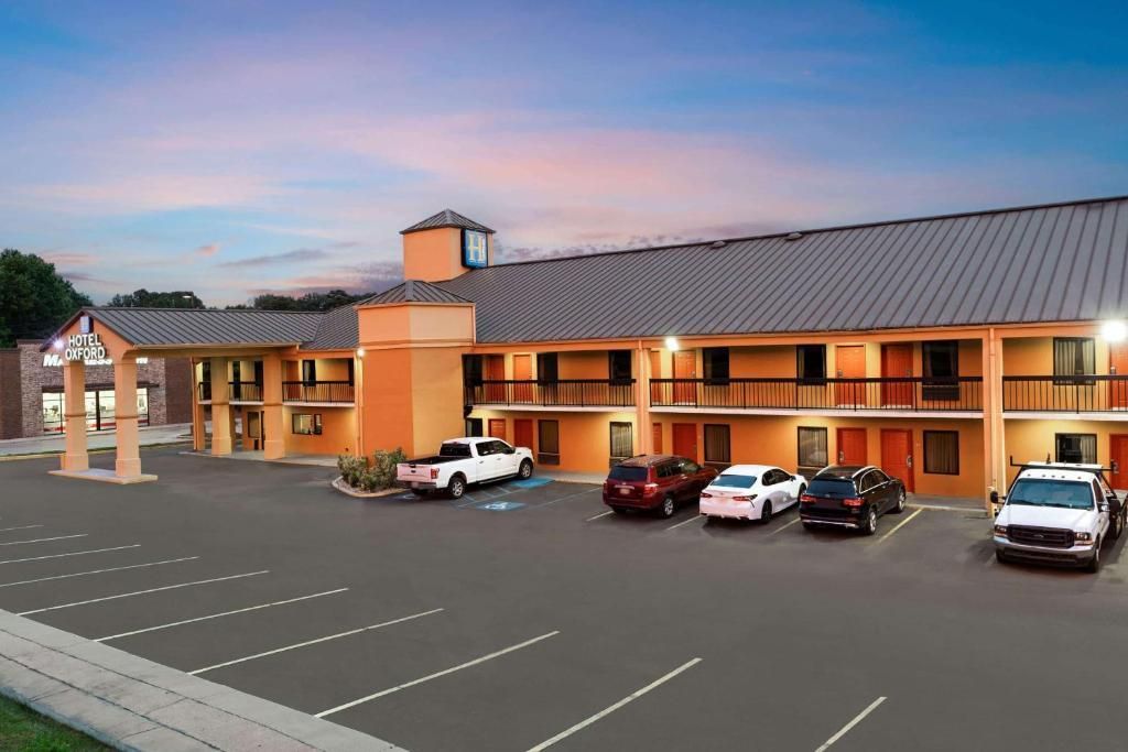 Motel exterior with parked cars under a twilight sky; parking lot in foreground.