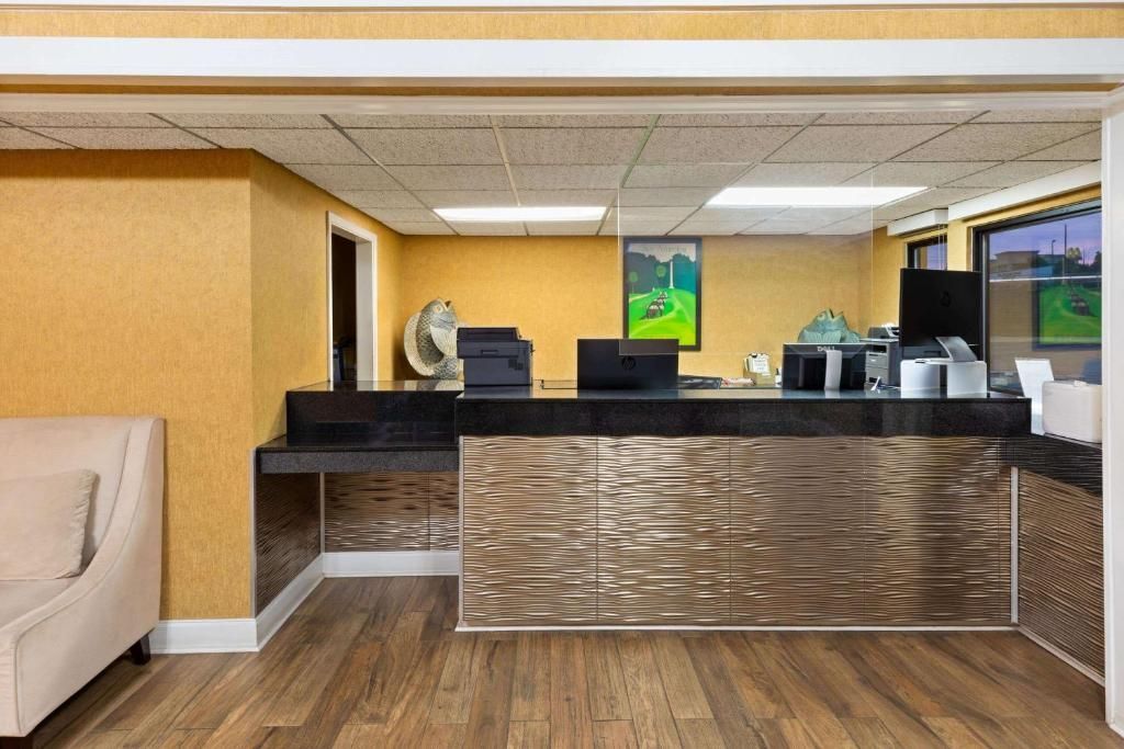 Hotel front desk with brown textured facade, black countertop, computers, and a small painting.