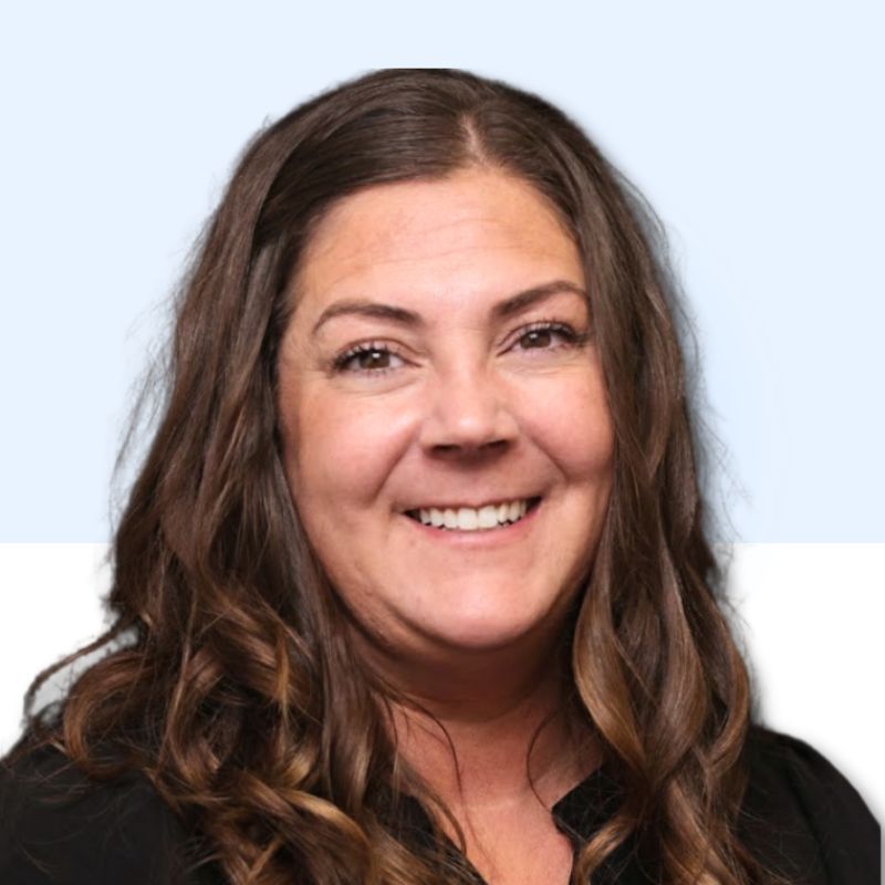 Woman with brown hair smiling at the camera, wearing a black top. Blue and white background.