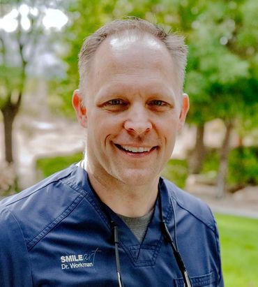 Dr. Taylor Workman in blue scrubs smiles outside. 