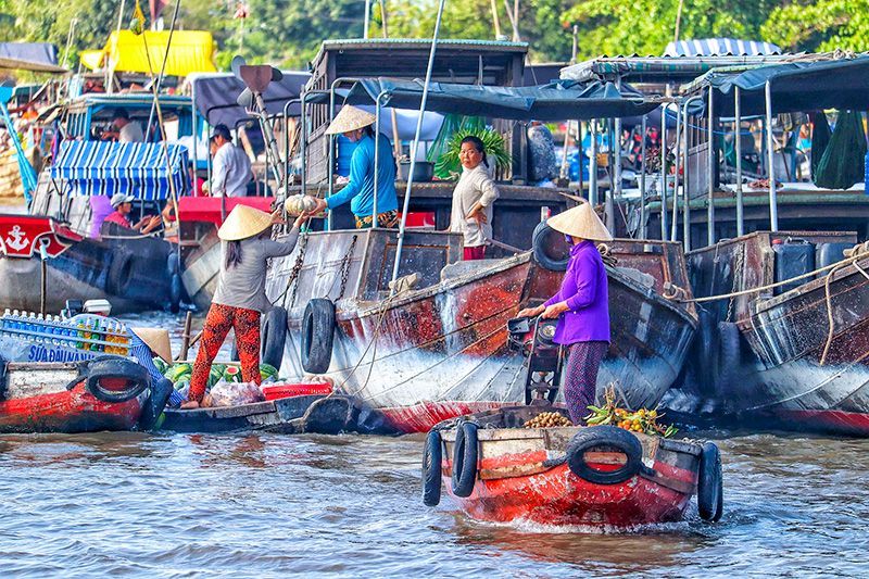 Visitors boarding a traditional wooden boat in Mekong Delta tour