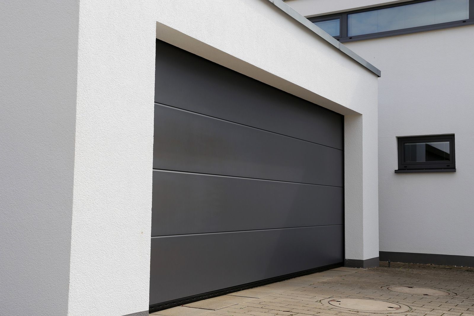 A gray garage door is in front of a white building
