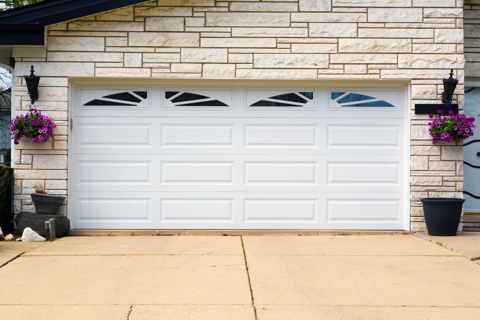 A white garage door is sitting in front of a brick house.