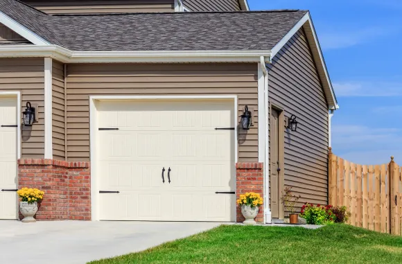 A house with a garage and a fence in front of it.