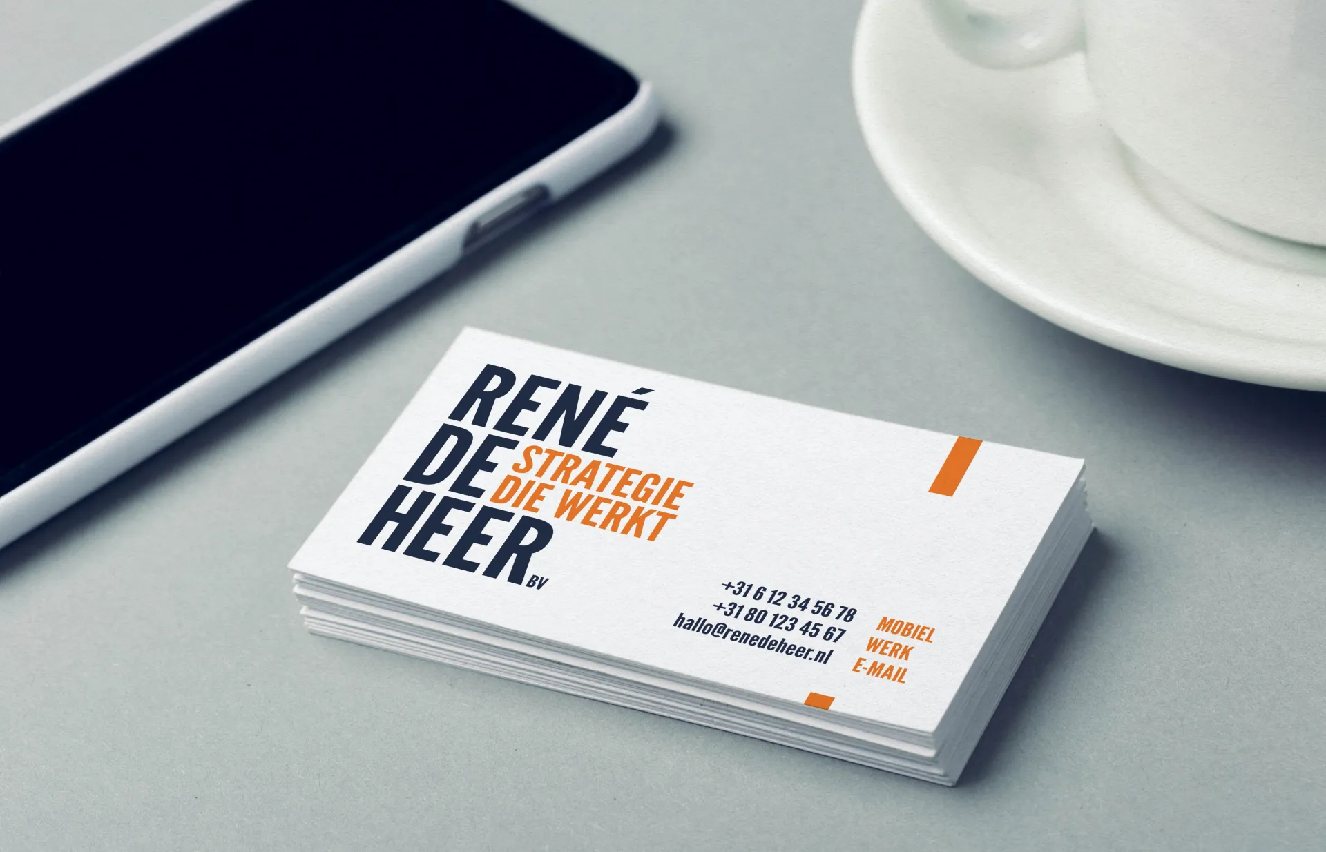 Sfeerbeeld met op tafel mobiel, stapeltje visitekaartjes en je ziet nog net een deel van een wit kopje