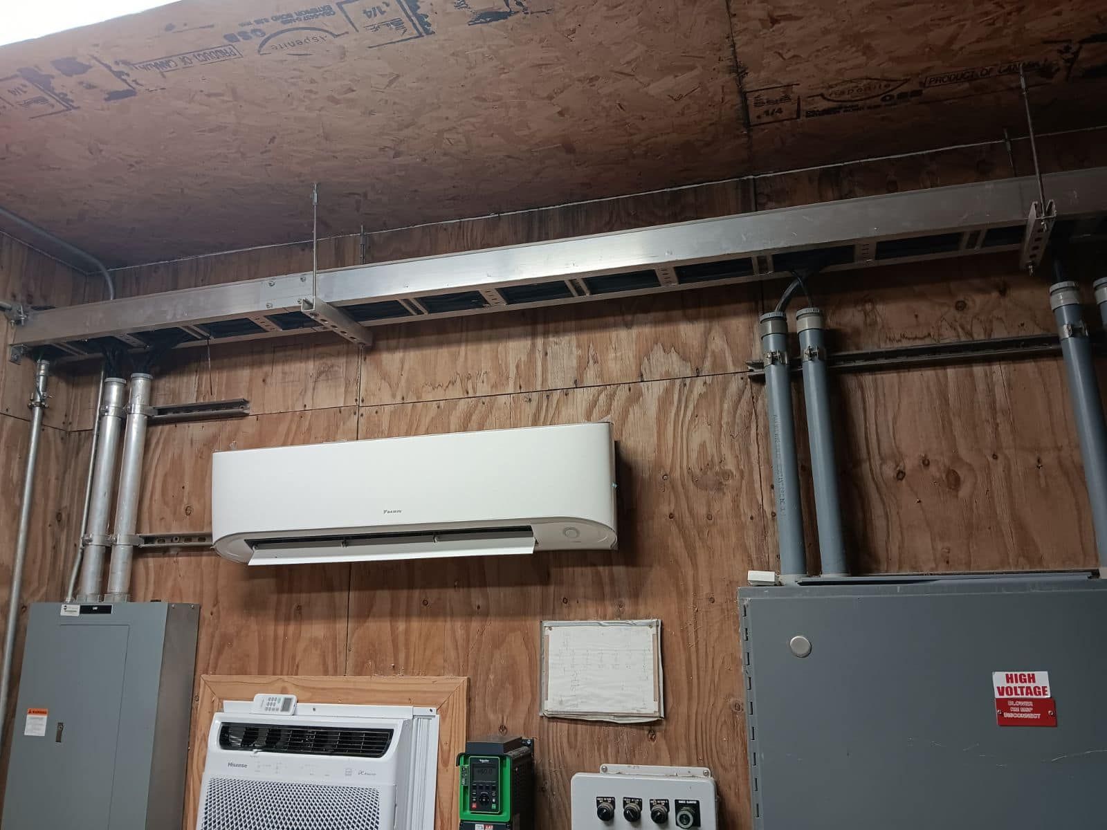 A white air conditioner is hanging on a wooden wall in a room.
