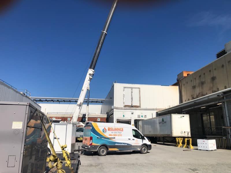A man is using a tablet while working on an air conditioner.