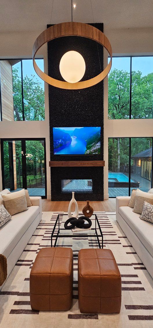 A living room with two couches , two ottomans , a coffee table and a television.