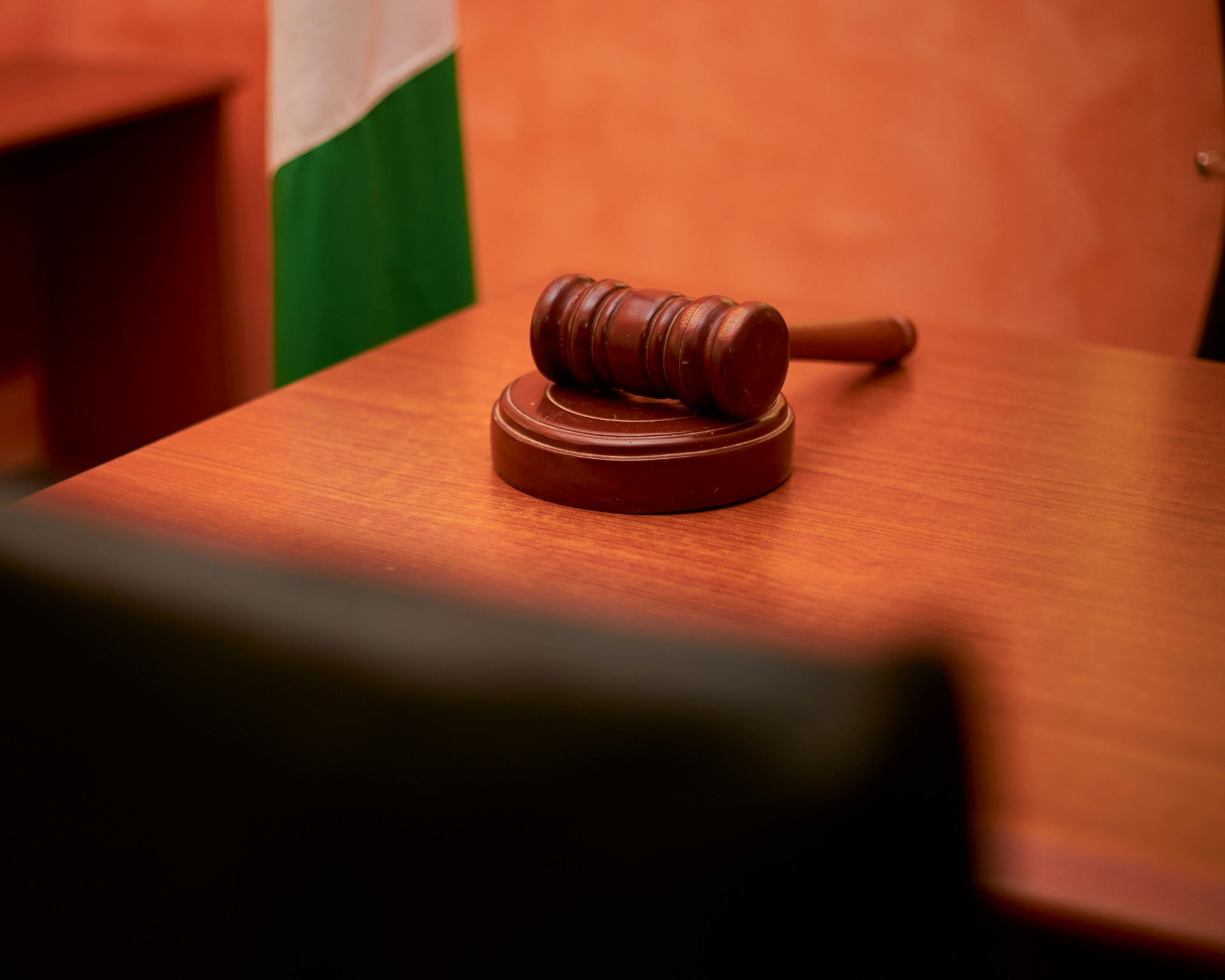 Judge’s gavel on a wooden desk in a courtroom, with an Indian flag in the background.