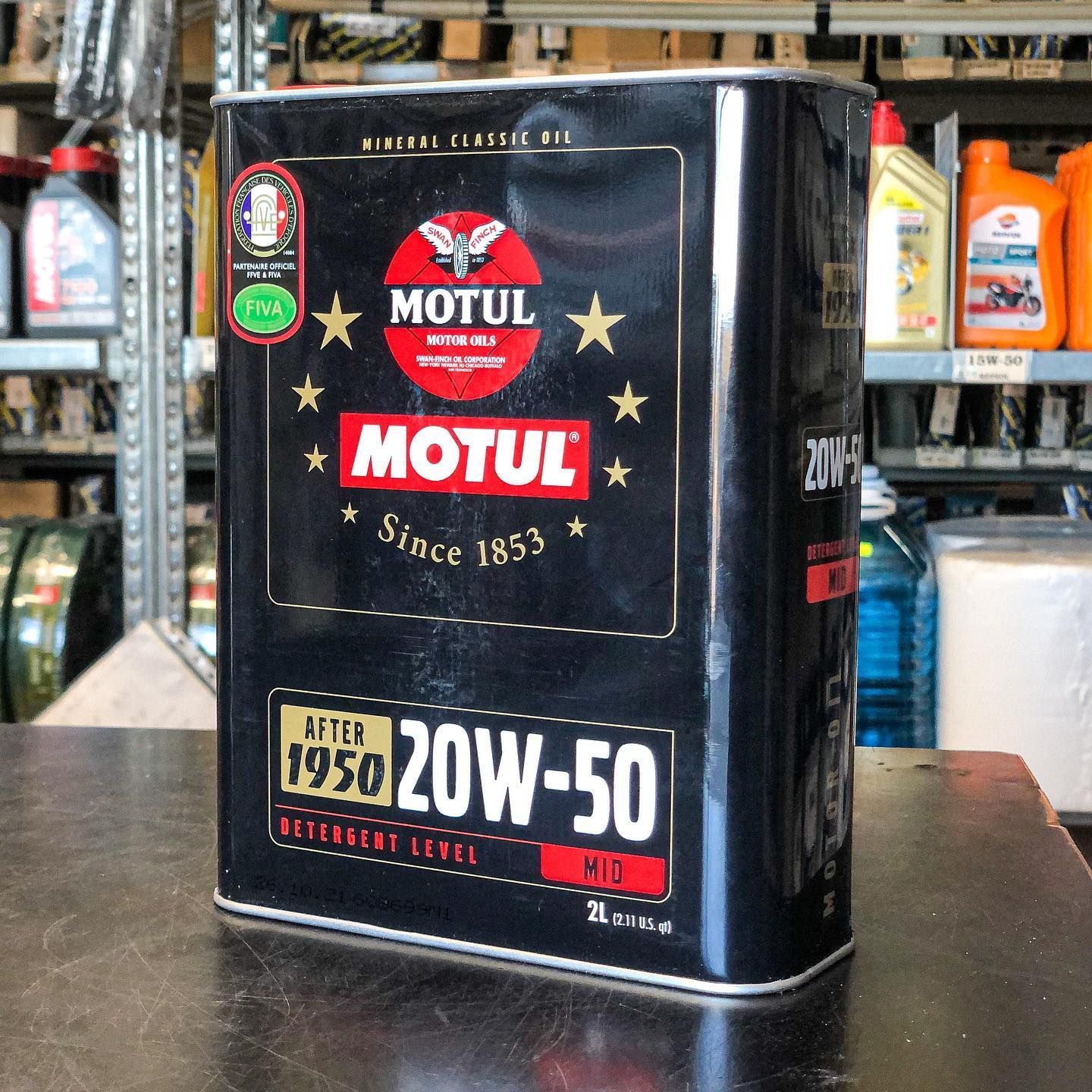 Una lattina rettangolare di olio motore Motul 20W-50 Classic su un bancone scuro in un negozio di ricambi auto.
